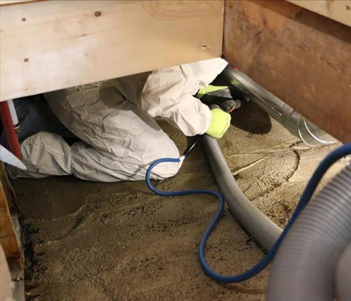 A technician extracting flood water and cleaning a crawlspace in Kelowna.