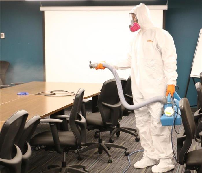 A Technician fogging disinfectant in an office space